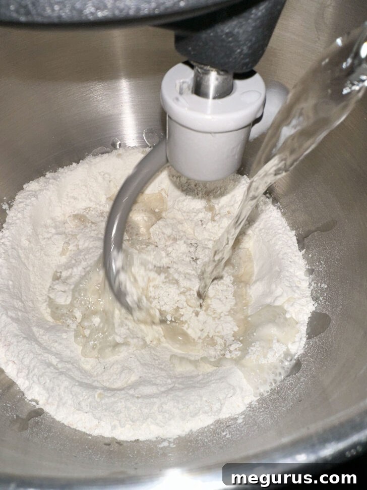 All focaccia dough ingredients (flour, water, yeast, oil, honey, salt) being added to a stand mixer bowl for mixing.