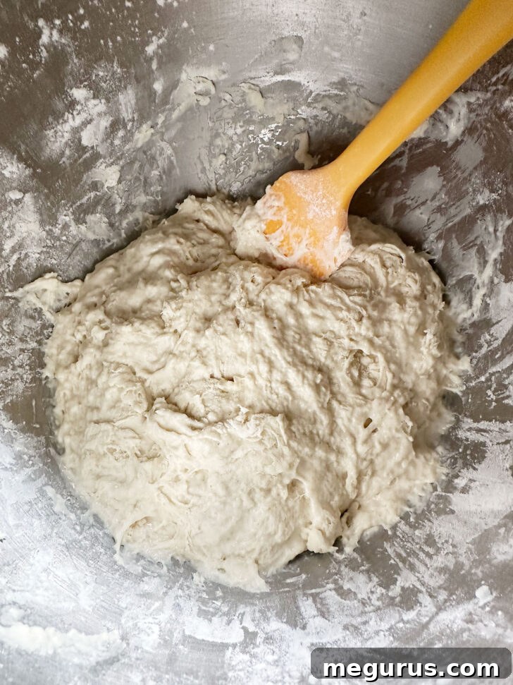 The focaccia dough after initial mixing, showing a very wet and shaggy consistency, in a stand mixer bowl.
