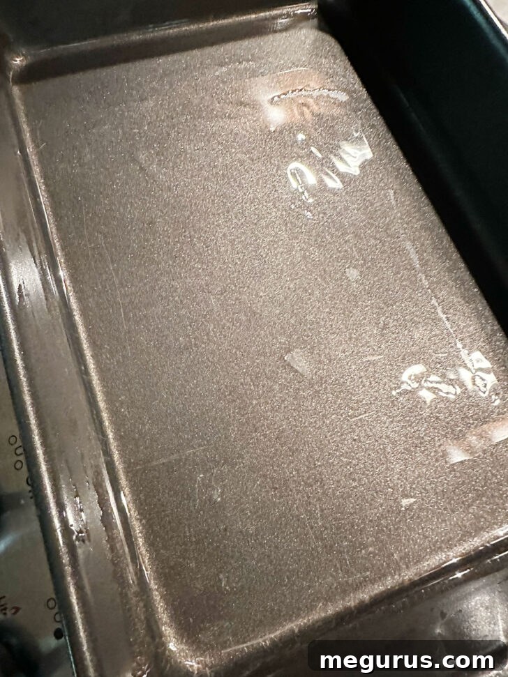 A 9x13-inch baking pan generously coated with vegetable oil, showing the base and sides glistening.