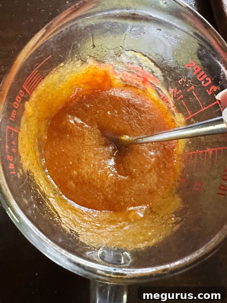 Pumpkin granola wet ingredients mixed up in measuring cup.