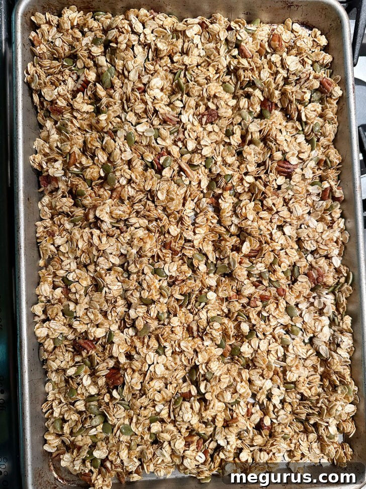 Pumpkin granola spread on baking sheet before baking.