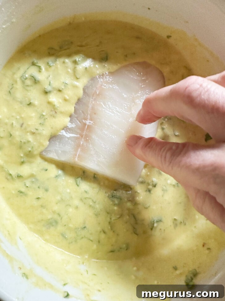 Adding fish to the sauce mixture in the bowl.