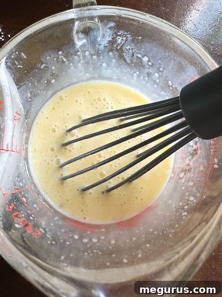 Whisking together the milk, eggs sugar and butter in a measuring cup.