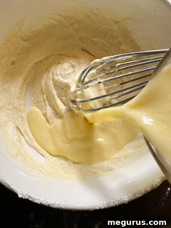 Adding the remaining egg mixture to the batter.