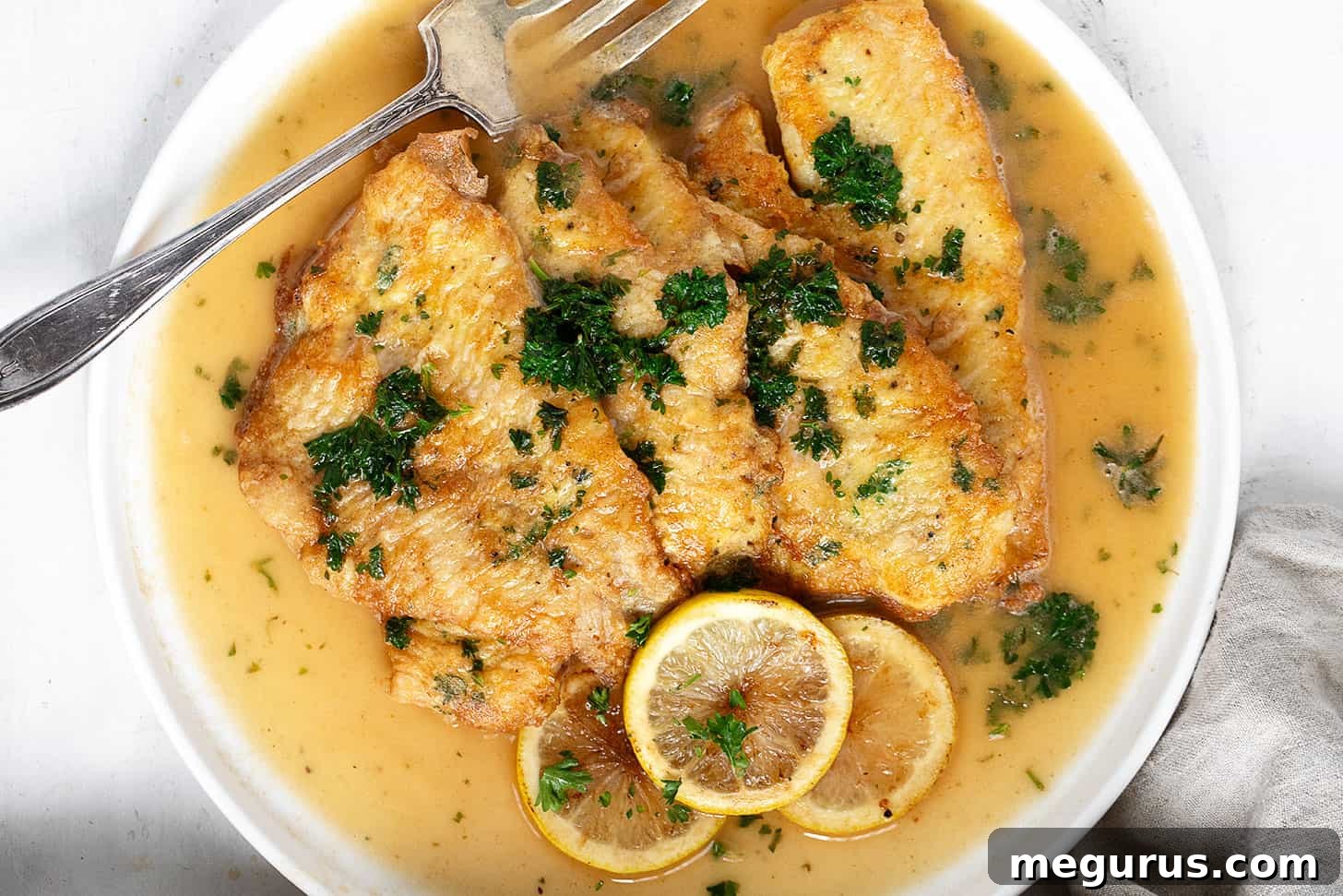 Crispy pan-fried Sole Francese fillets with lemon slices and parsley garnish on a serving platter.