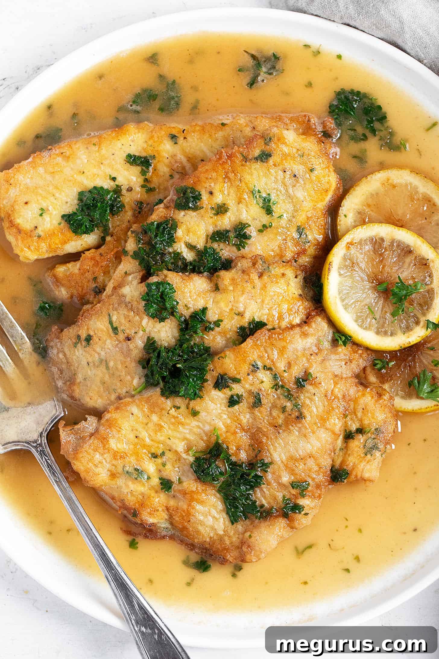 A beautifully plated dish of Sole Francese, showcasing the golden-brown fillets, vibrant lemon slices, and fresh parsley garnish.