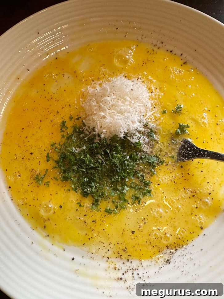 Mixing eggs, Parmesan cheese, and fresh parsley in a bowl for the sole coating.