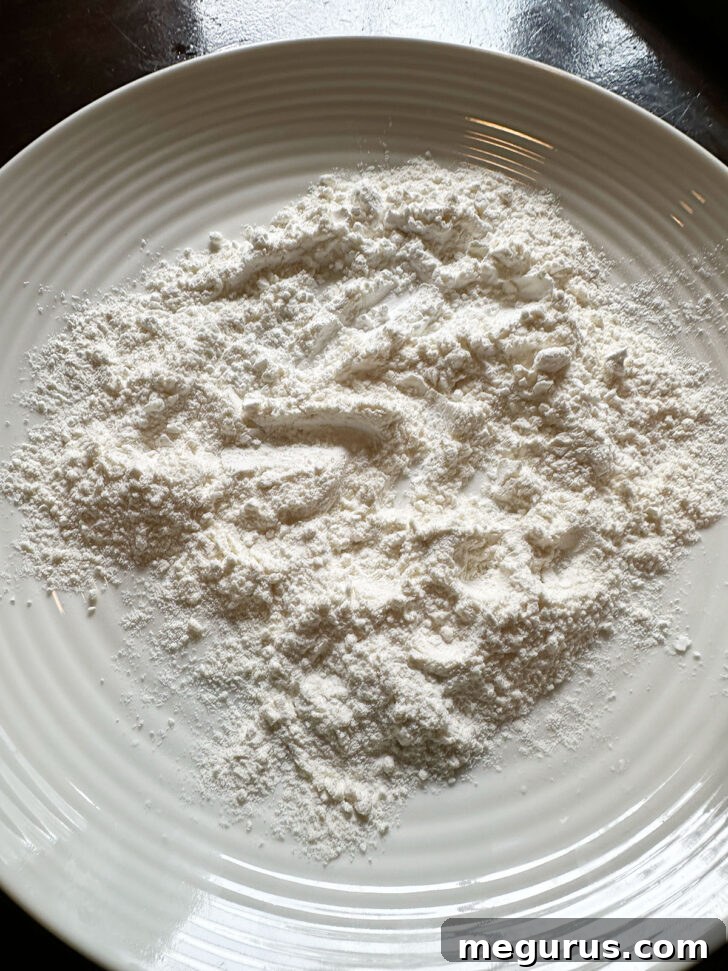 All-purpose flour spread on a plate, ready for dredging fish fillets.