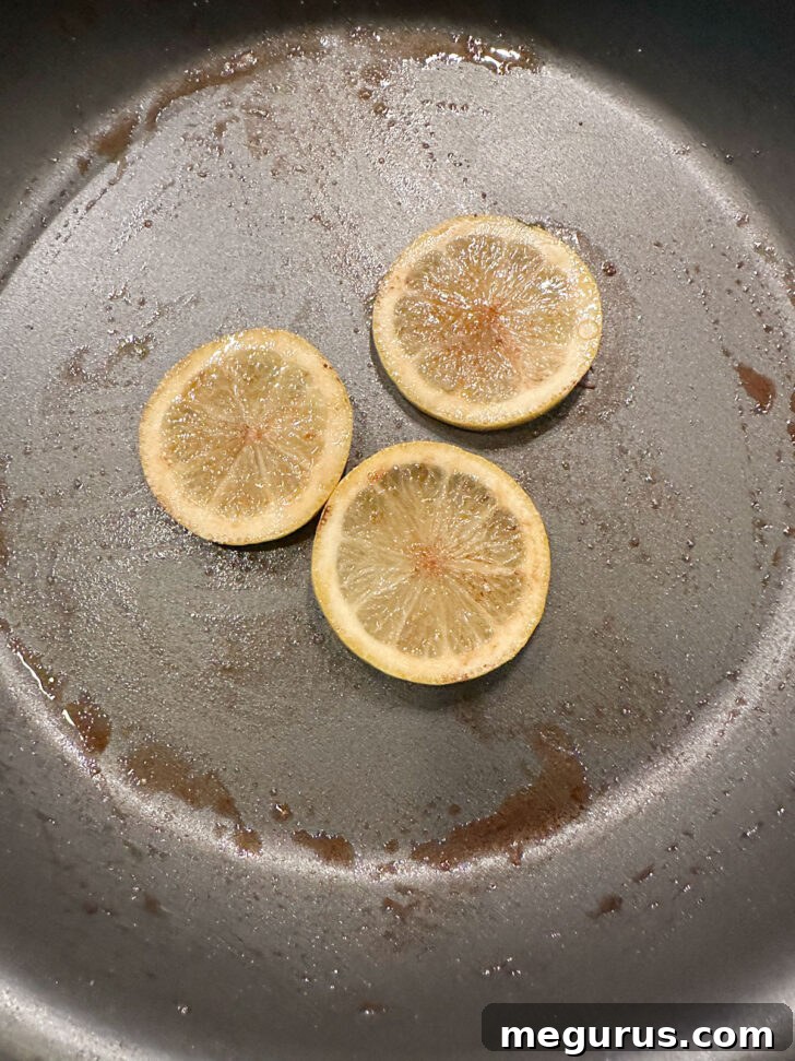 Lemon slices being browned in a clean skillet, adding a caramelized citrus flavor.