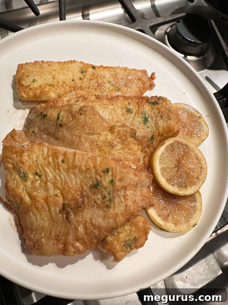 Browned lemon slices removed from the skillet and added to the warm plate with the sole fillets.