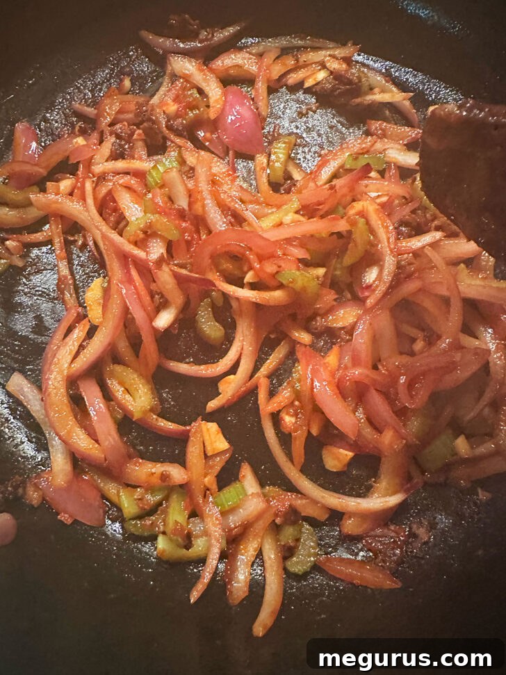 The vegetables cooked together with the tomato paste in the skillet.