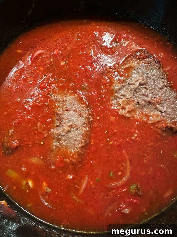 The browned steaks returned to the skillet with the sauce.