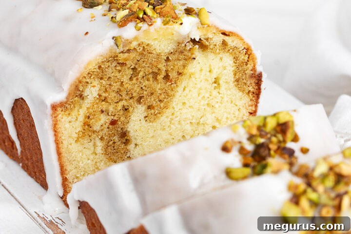 A beautifully presented slice of Lemon Pistachio Loaf Cake, showcasing its vibrant layers and glossy glaze.
