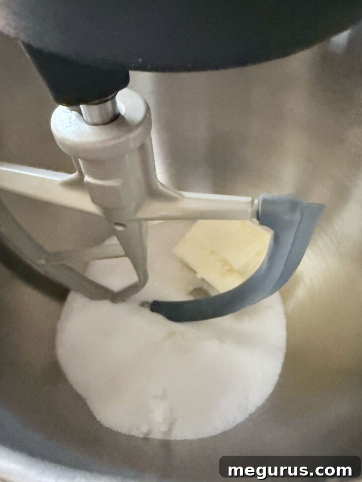 Softened butter and granulated sugar being creamed together in a stand mixer bowl, turning light and fluffy.
