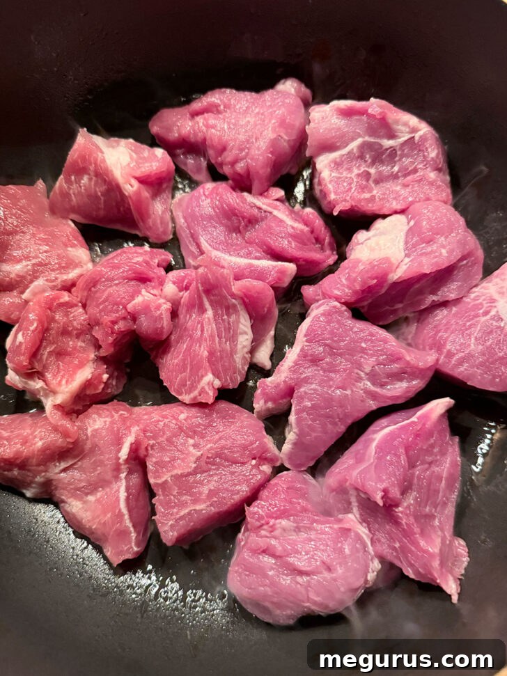 Pork pieces placed into hot skillet.