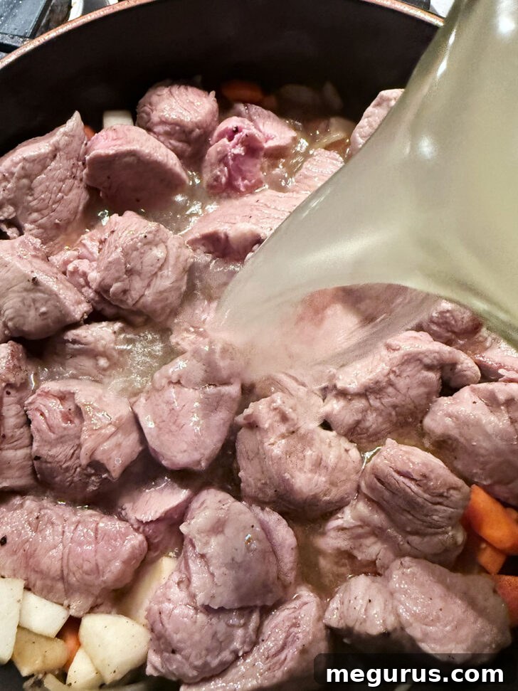 Adding chicken broth to the skillet.