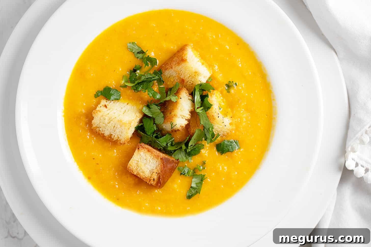 Carrot coriander soup in soup bowl with croutons.