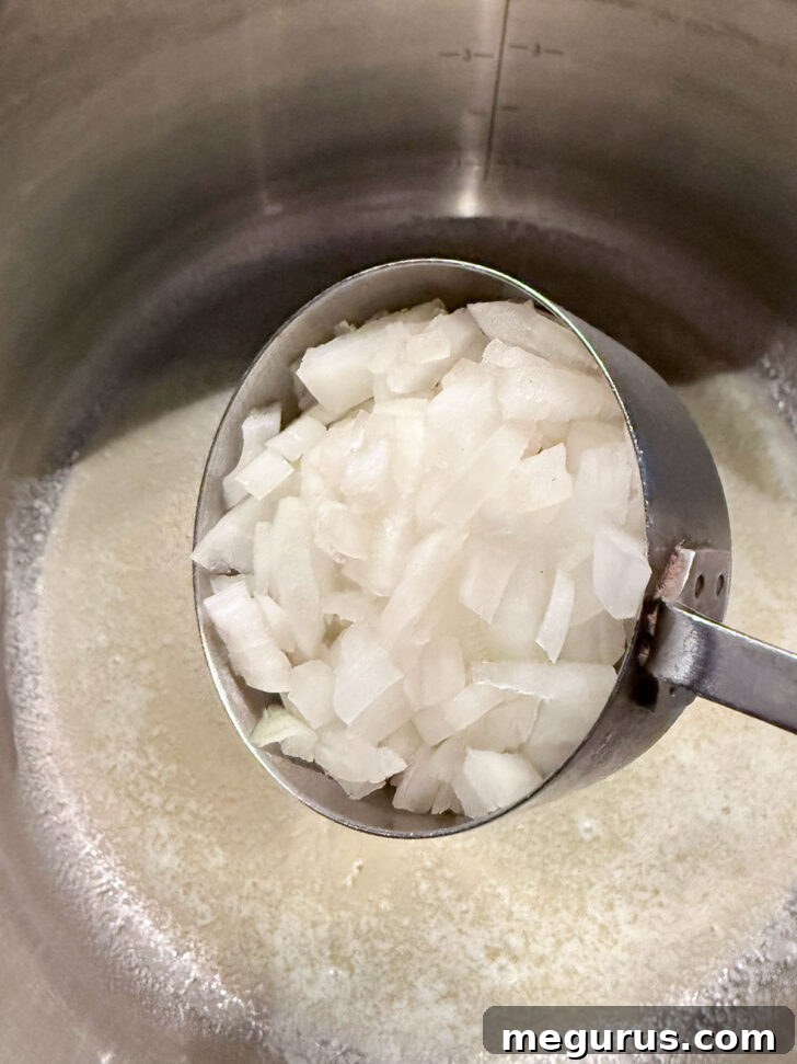 Adding onion to melted butter in soup pot.