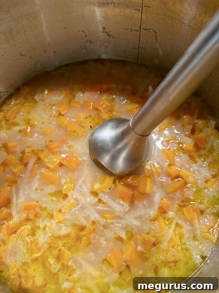 Using an immersion blender to puree the soup.