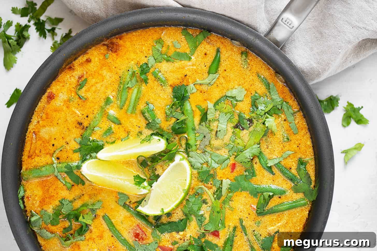 Creamy Chicken Peanut Butter Curry served in a large skillet, garnished with fresh herbs and lime slices, ready to be enjoyed.