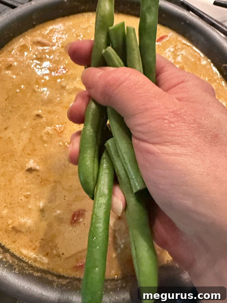 Fresh green beans added to the nearly cooked chicken peanut butter curry.