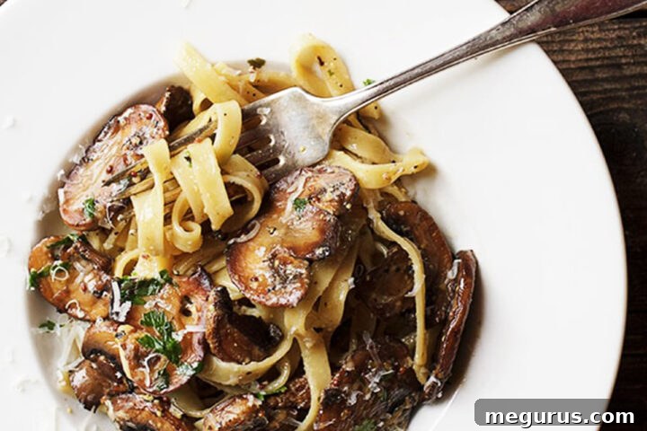 A delicious bowl of creamy mustard pasta with mushrooms, garnished with fresh herbs.