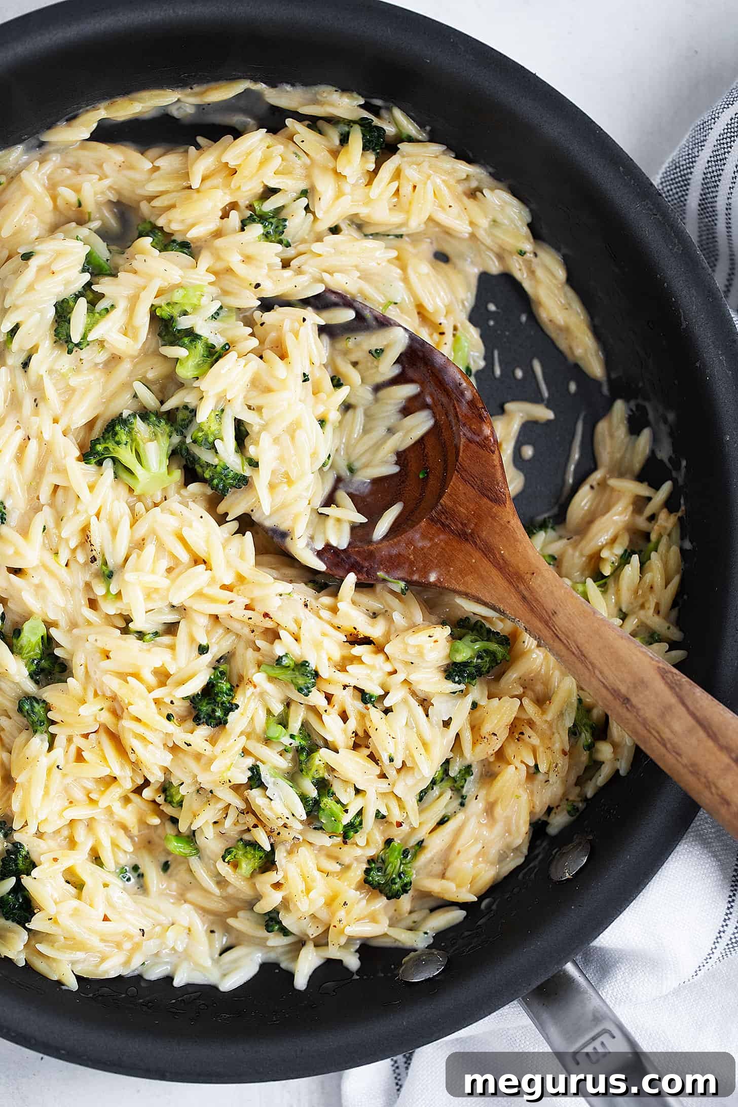 Broccoli cheddar orzo in skillet, garnished and ready to serve.