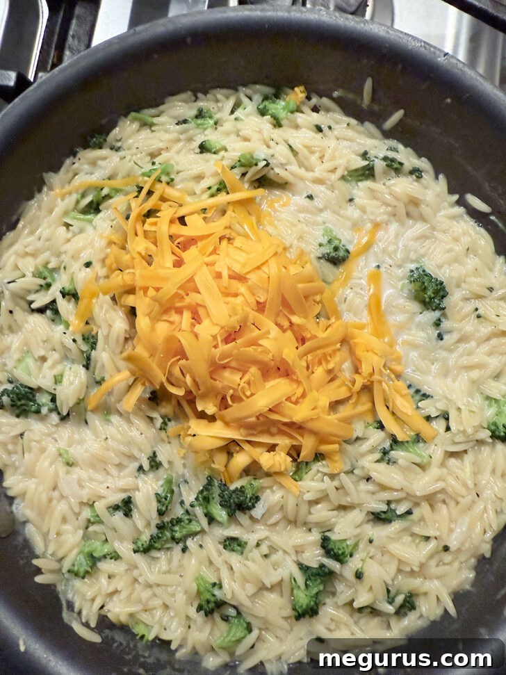 Adding cheddar cheese to the skillet.