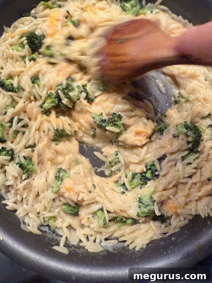 Stirring the cheese into the orzo to melt.