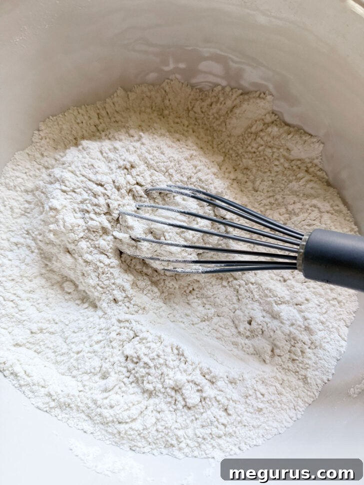 Flour mixture in a bowl with a whisk, ready for wet ingredients.