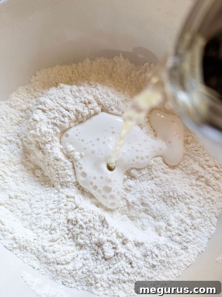 Pouring beer into the flour mixture in a mixing bowl.