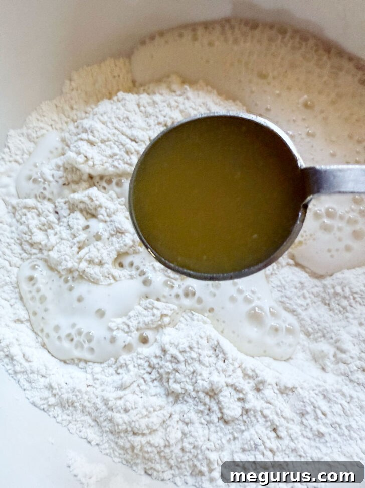 Adding a spoonful of honey butter to the partially mixed dough.
