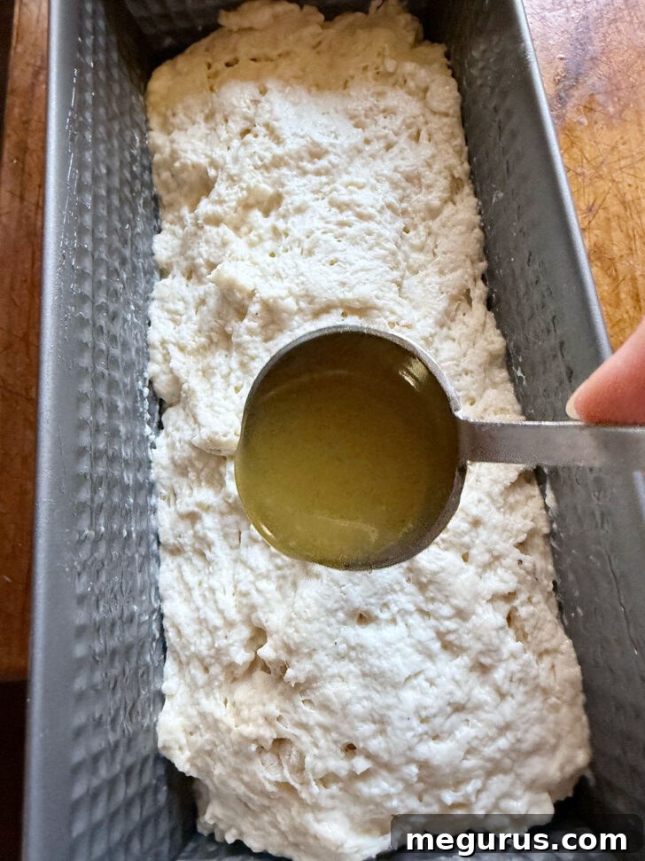 Drizzling remaining honey butter over the dough in the loaf pan before baking.