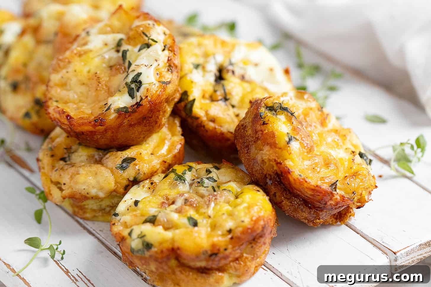 Crustless mini quiche on serving board, garnished with fresh herbs.