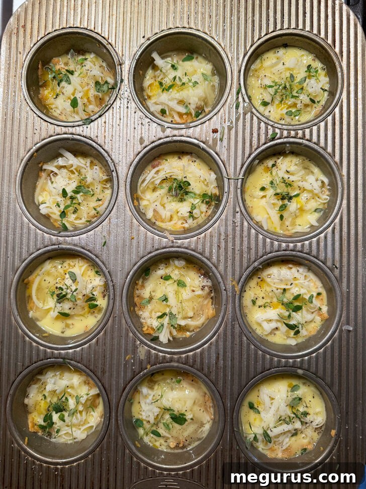 Fresh herbs, like thyme, sprinkled on top of mini quiches before baking.