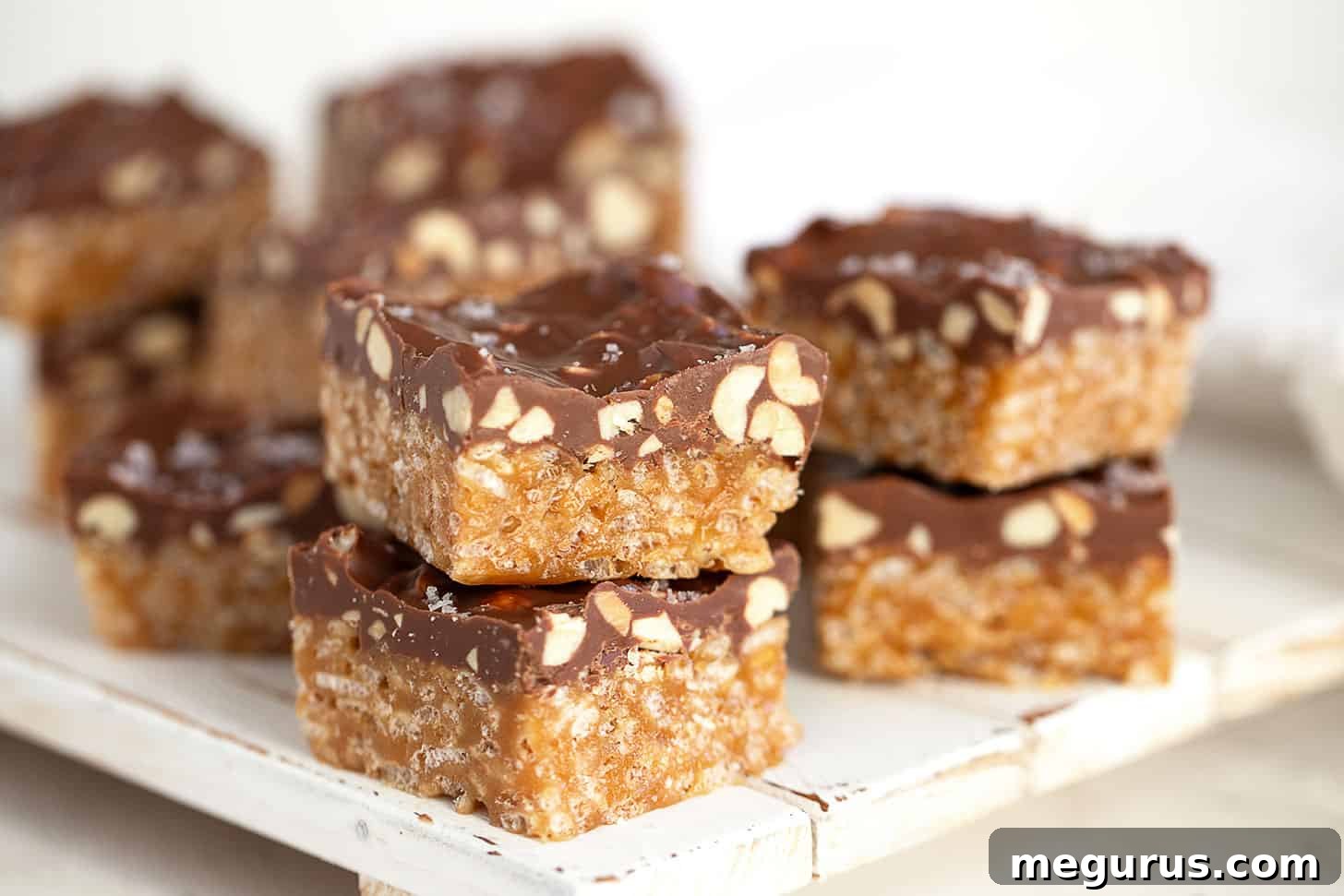 Sweet Marie bars cut into squares on a wooden serving board, showcasing the crispy base, peanuts, and chocolate topping.