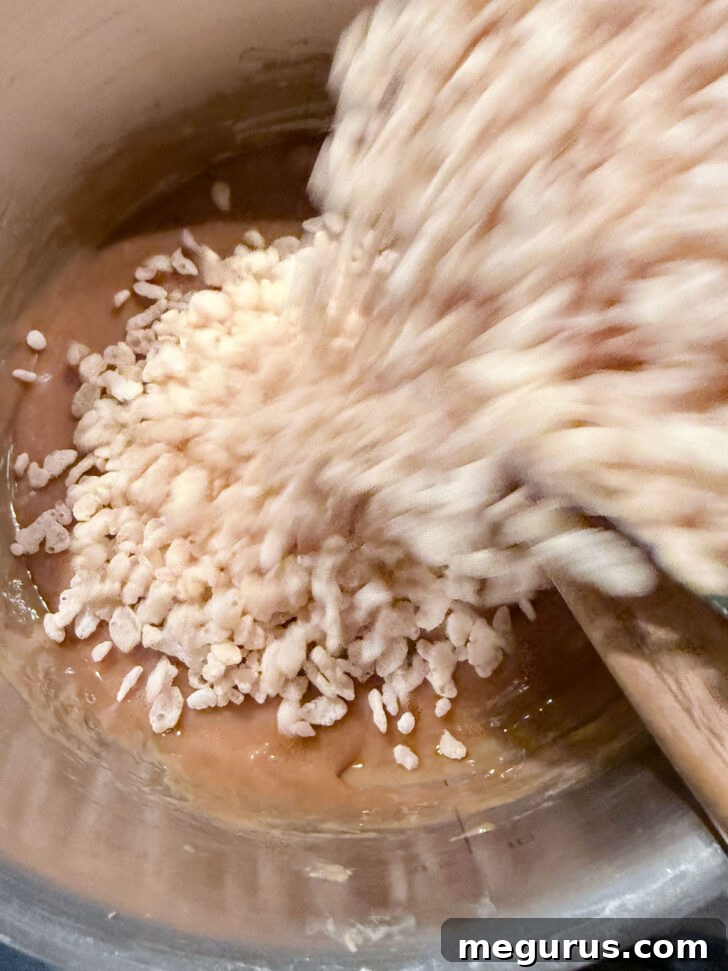Adding rice krispies to the peanut butter mixture.