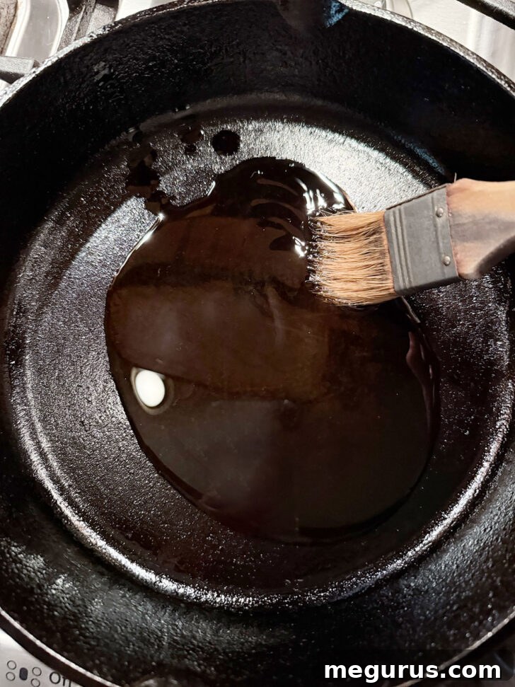 Olive oil being brushed onto the bottom and sides of a cast-iron skillet.