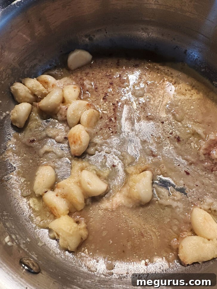 Garlic cloves and savory pan juices remaining in the skillet, forming the base for the gravy.