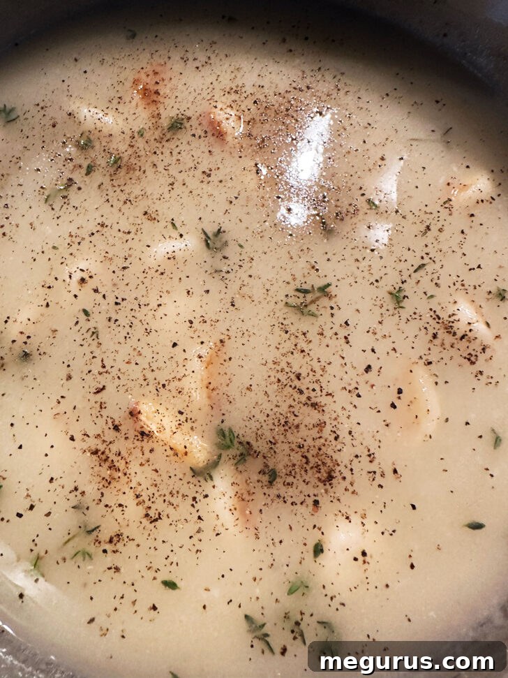 Seasoning the simmering gravy with fresh thyme, salt, and pepper.