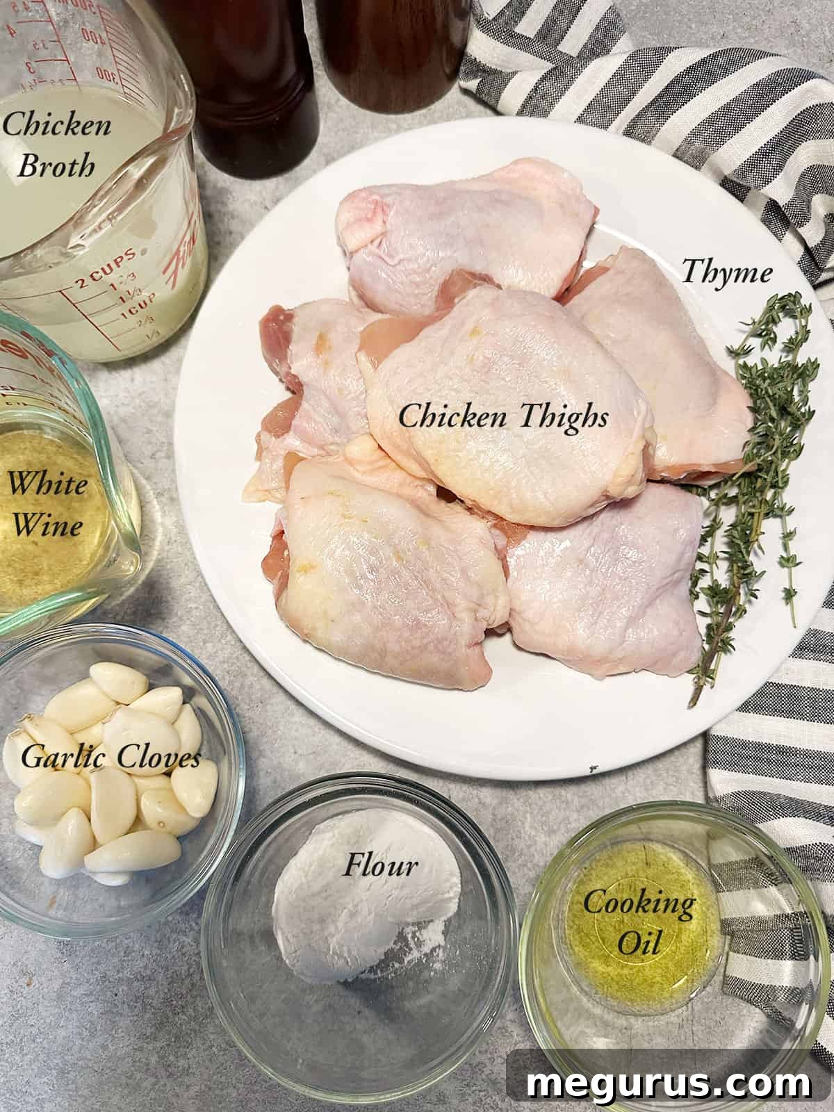 A selection of fresh ingredients laid out, including chicken thighs, garlic cloves, fresh thyme, and other pantry staples, ready for making rustic garlic chicken and gravy.