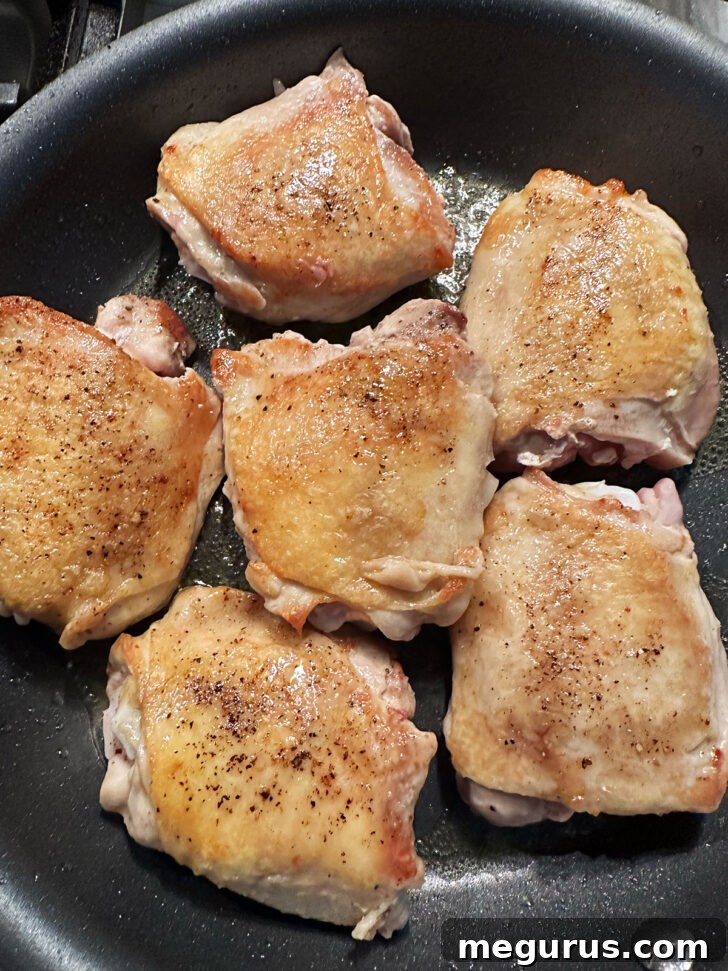 Chicken thighs after being flipped, showing a beautiful golden-brown, crispy skin.