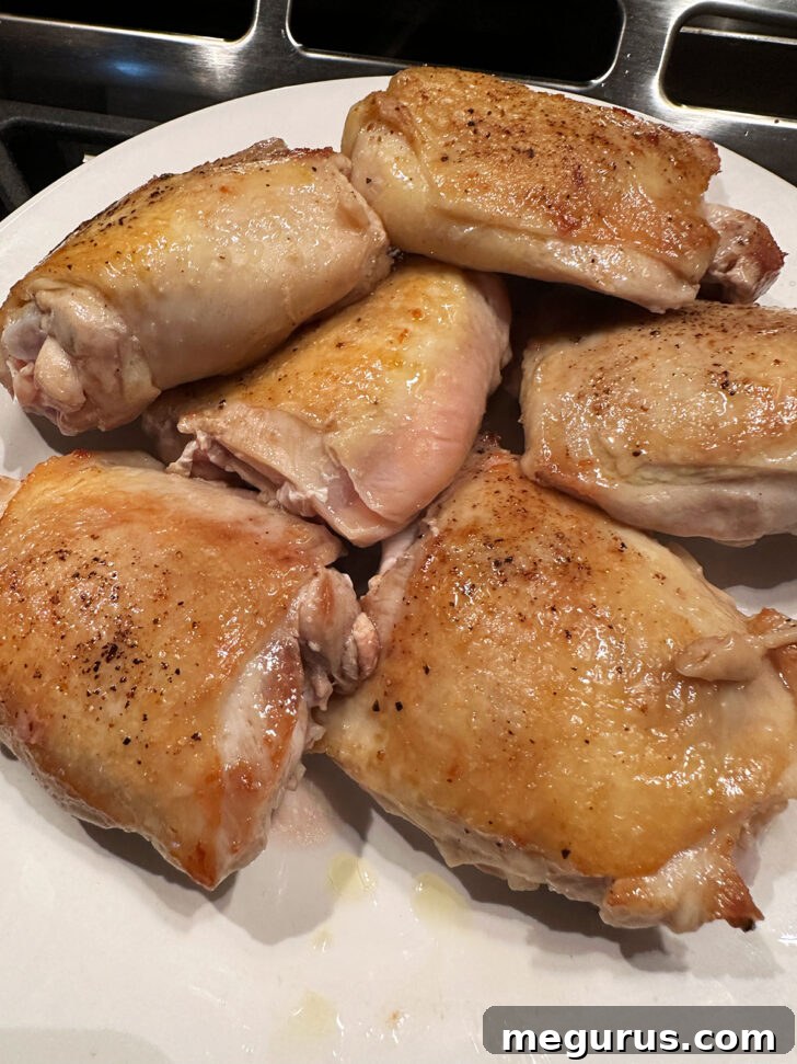 Perfectly browned chicken thighs carefully removed from the skillet and placed onto a clean plate.