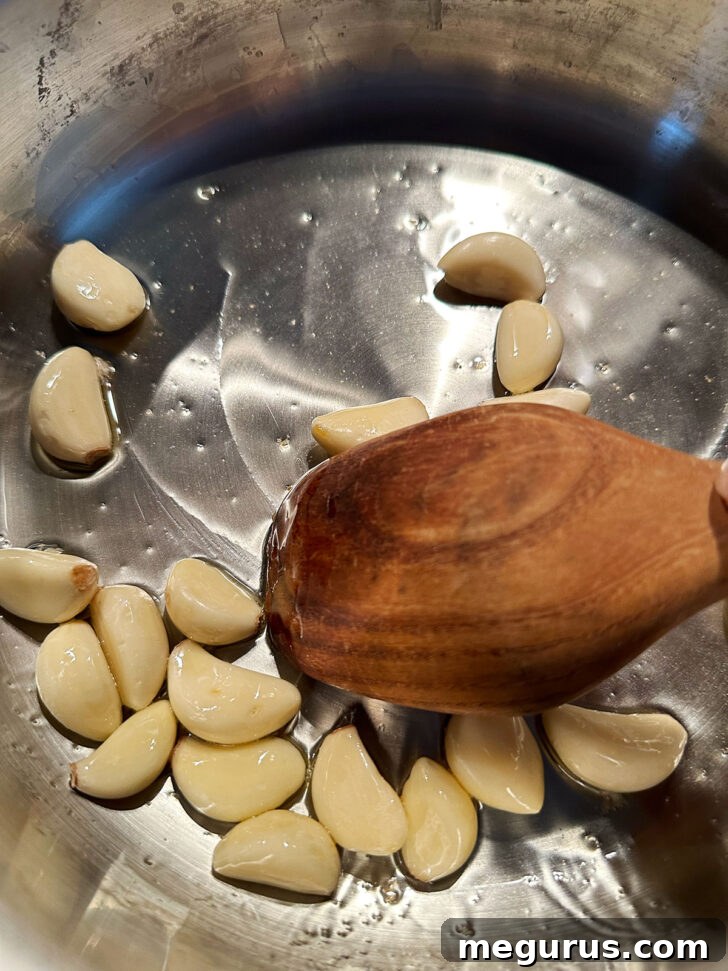Whole garlic cloves added to the hot skillet, ready to be cooked.