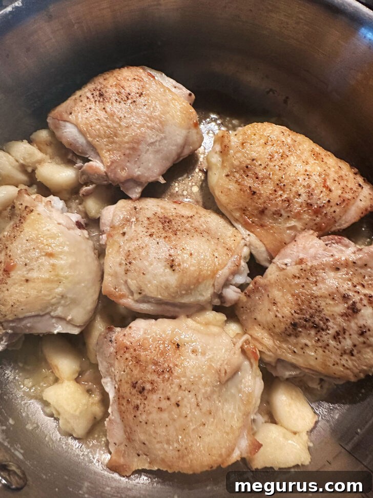 A skillet freshly removed from the oven, showing cooked chicken and garlic.