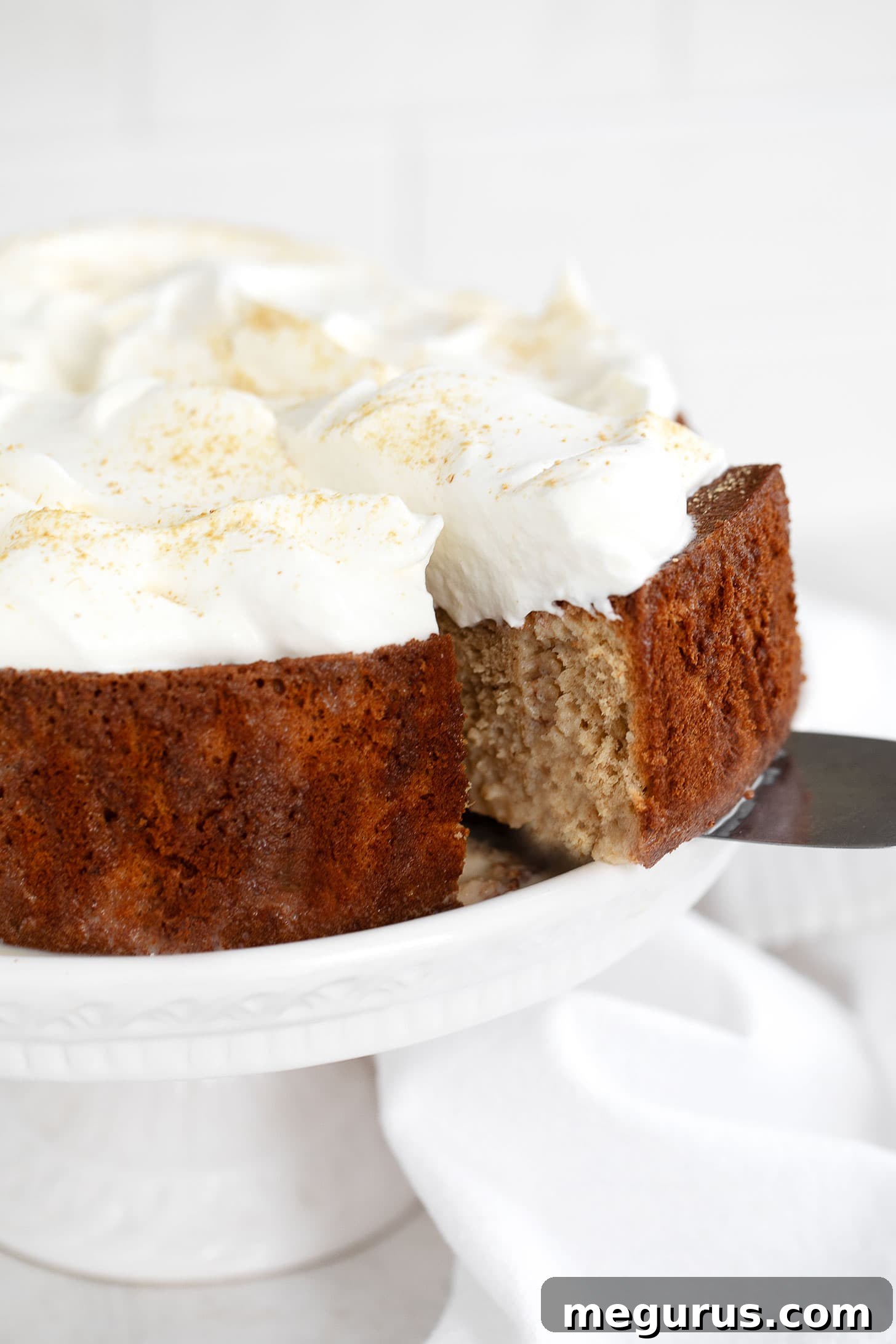 Gingerbread tres leches cake sliced on cake stand, ready to be served.