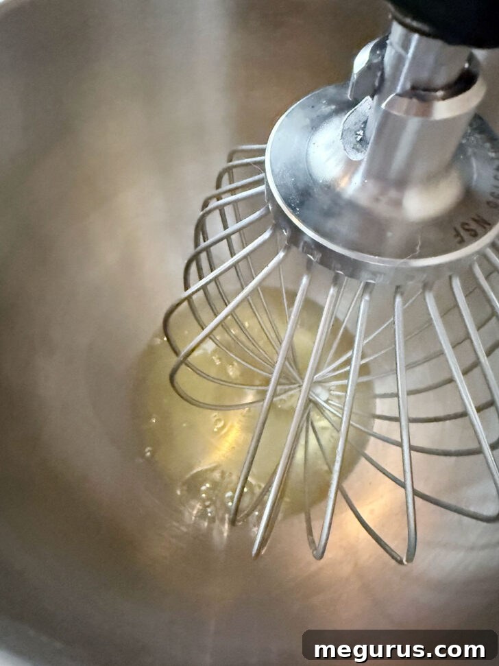 Egg whites in mixer bowl with whisk attachment, beginning to foam.