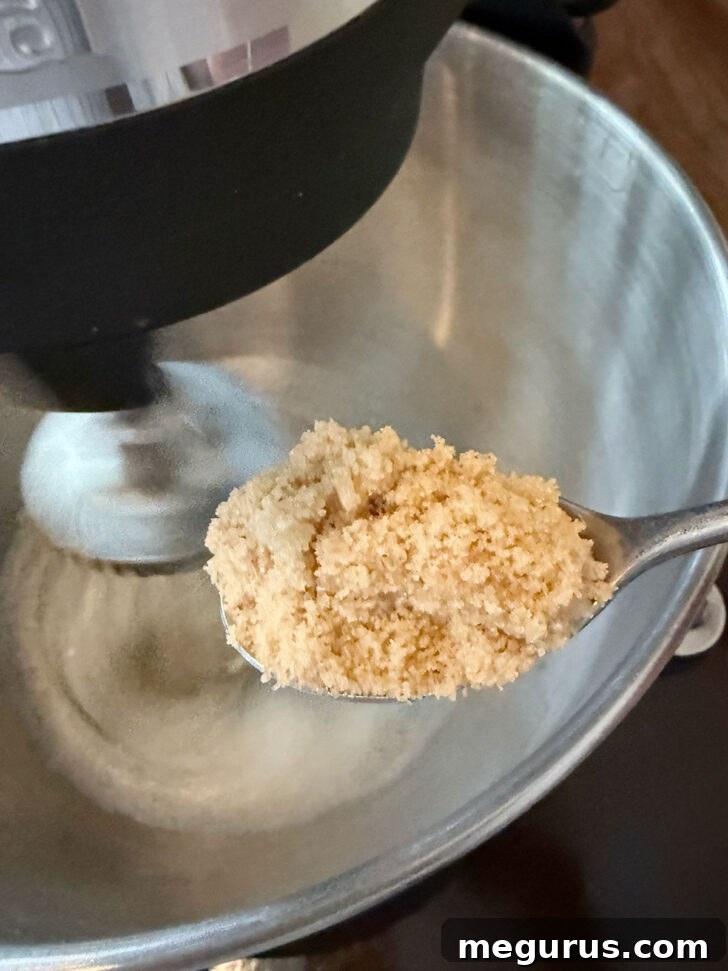 Adding brown sugar to the foamy egg whites in a mixer.