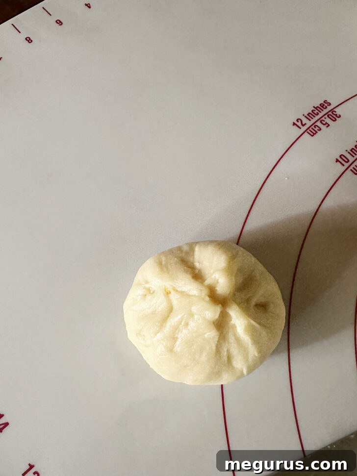 Forming dough pieces into smooth, round buns.