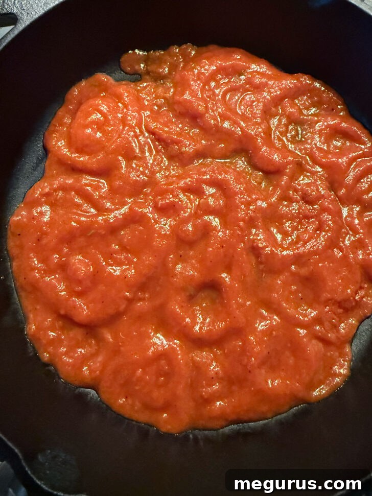 A layer of rich marinara sauce coating the bottom of a cast iron skillet.